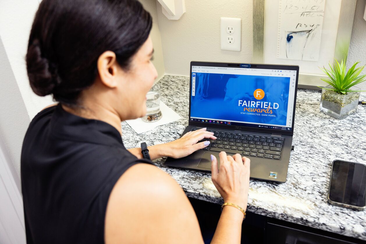 A woman uses Fairfield Rewards on a laptop